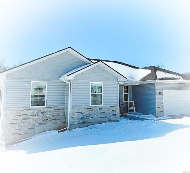 ranch-style house featuring a garage and stone siding