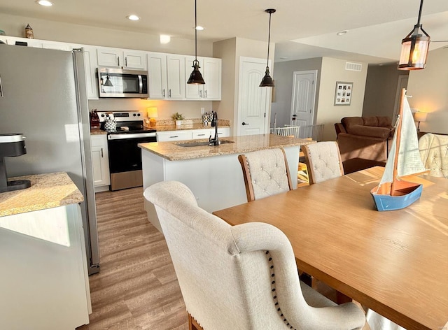 kitchen featuring recessed lighting, a kitchen island, a sink, appliances with stainless steel finishes, and light wood-type flooring