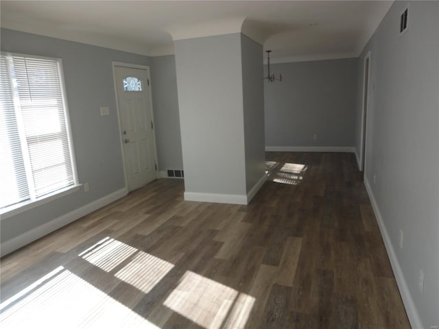 entryway with an inviting chandelier and dark wood-type flooring