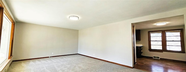 carpeted spare room with visible vents and baseboards