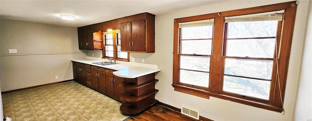 bar featuring light floors, baseboards, visible vents, and a sink