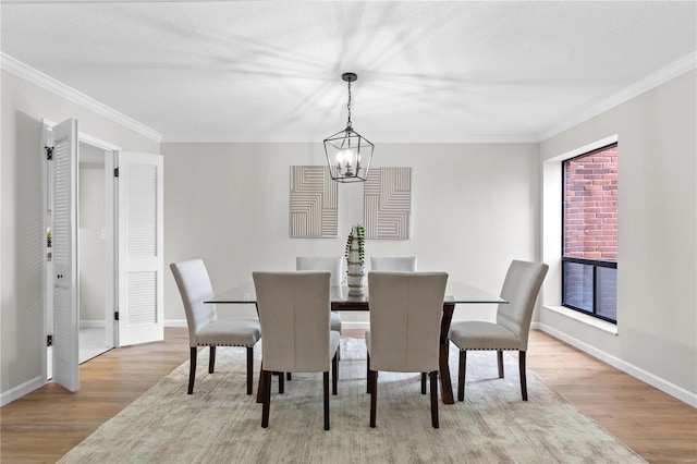 dining area with a notable chandelier, light hardwood / wood-style flooring, ornamental molding, and a textured ceiling