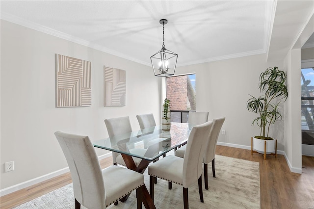 dining area with ornamental molding, hardwood / wood-style floors, and a notable chandelier