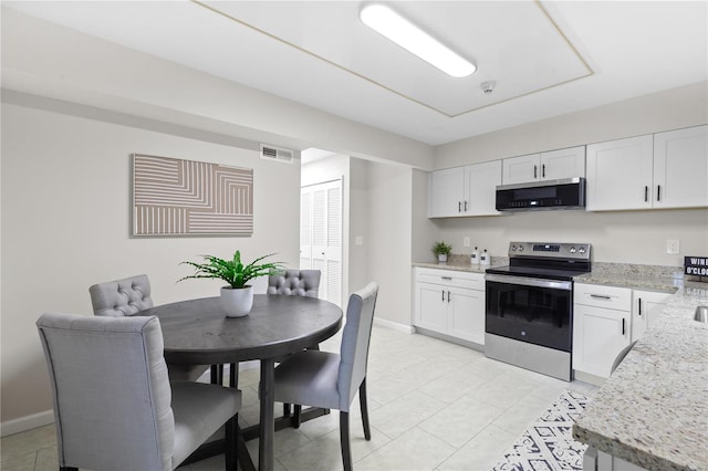 kitchen with stainless steel appliances, light tile patterned flooring, light stone countertops, and white cabinets