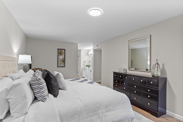 bedroom with connected bathroom and light wood-type flooring