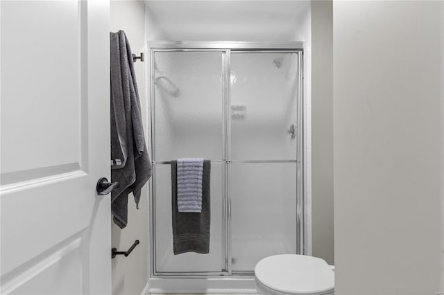 bathroom featuring toilet and a shower with door