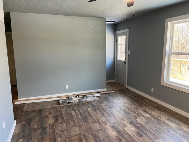 empty room with dark wood-type flooring, a textured ceiling, and ceiling fan