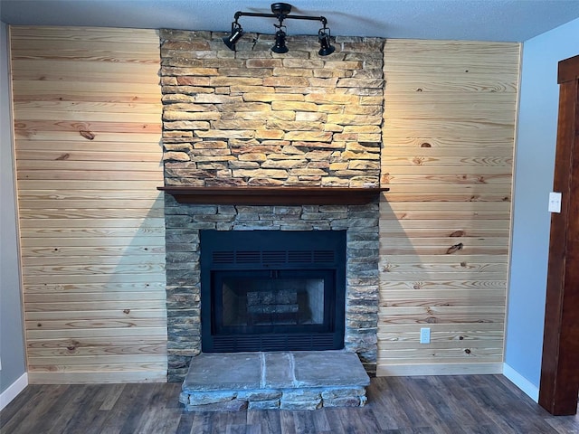 details featuring a stone fireplace, hardwood / wood-style floors, a textured ceiling, and wooden walls