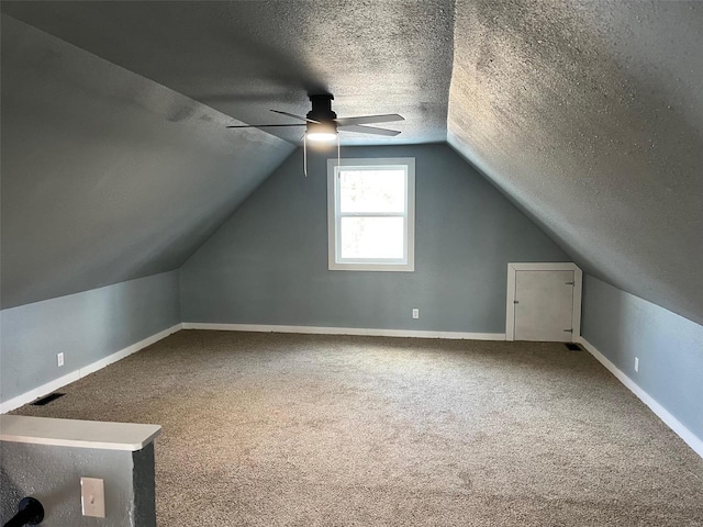 bonus room featuring ceiling fan, lofted ceiling, carpet floors, and a textured ceiling