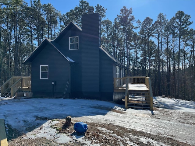 snow covered back of property with a deck