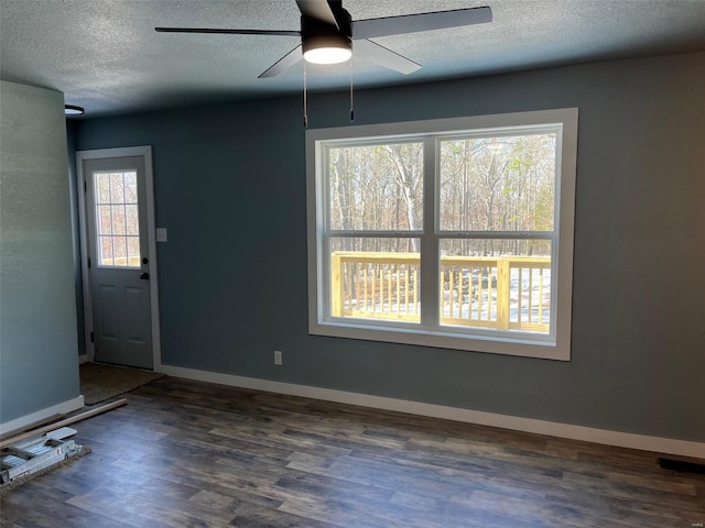 unfurnished dining area featuring dark wood-style floors, baseboards, and a textured ceiling