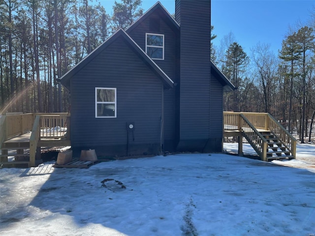 snow covered property featuring a deck and a chimney