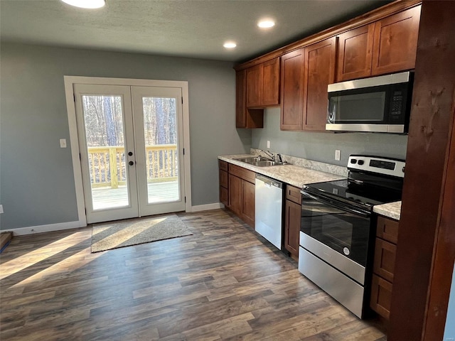 kitchen with baseboards, a sink, stainless steel appliances, light countertops, and french doors