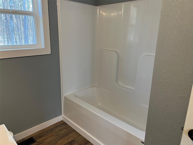 bathroom with visible vents, baseboards, wood finished floors, and a textured wall