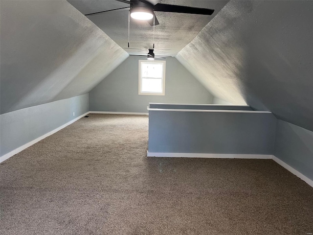 bonus room with lofted ceiling, a textured ceiling, carpet floors, baseboards, and ceiling fan