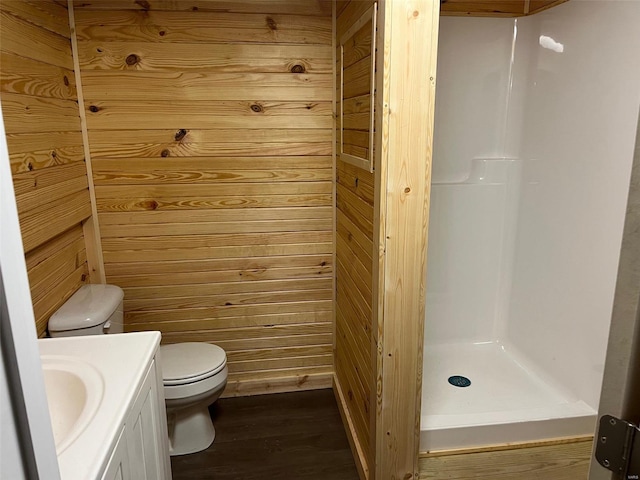 full bath with toilet, wood finished floors, wood walls, a shower stall, and vanity