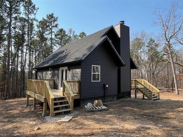 back of property featuring a deck, a chimney, and roof with shingles