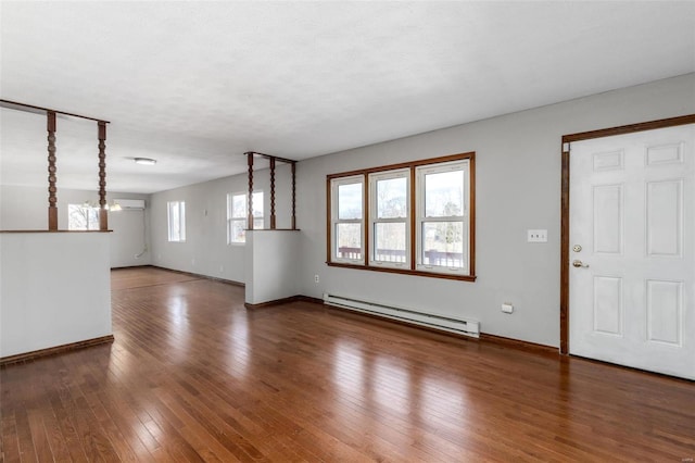 unfurnished living room featuring a chandelier, baseboard heating, and dark hardwood / wood-style flooring