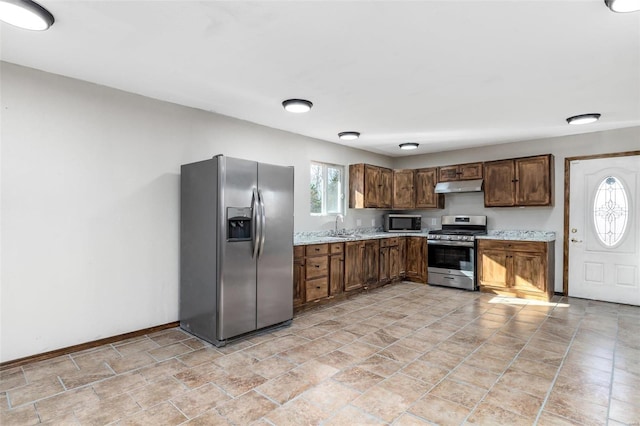 kitchen featuring sink, stainless steel appliances, and light stone countertops