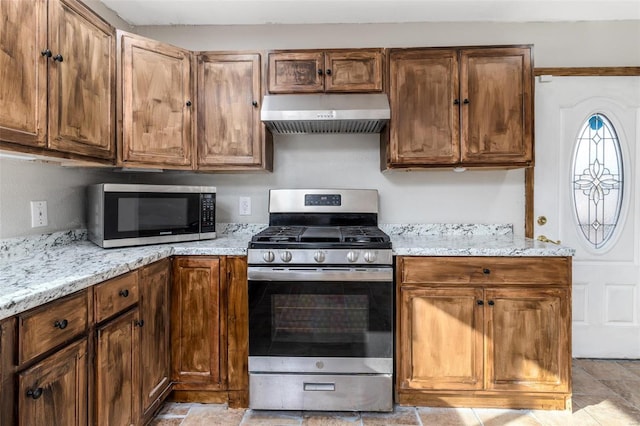 kitchen featuring light stone countertops, appliances with stainless steel finishes, and extractor fan