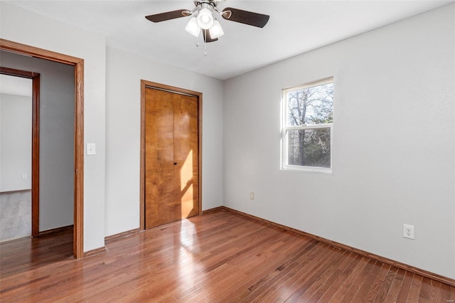 unfurnished bedroom with hardwood / wood-style flooring, a closet, and ceiling fan