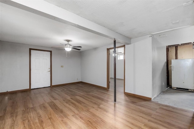 basement with ceiling fan, a textured ceiling, and light wood-type flooring