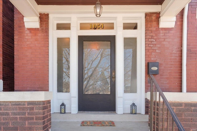 view of exterior entry featuring brick siding and covered porch