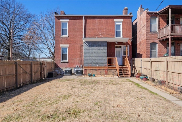 back of property with a yard, central air condition unit, brick siding, and a fenced backyard