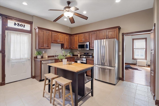 kitchen with a sink, appliances with stainless steel finishes, recessed lighting, and radiator heating unit