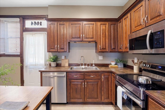 kitchen with dark countertops, brown cabinets, stainless steel appliances, and a sink