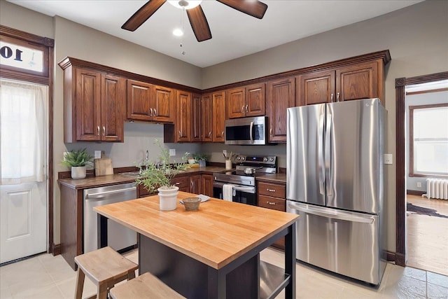 kitchen featuring a kitchen breakfast bar, wooden counters, radiator, and appliances with stainless steel finishes