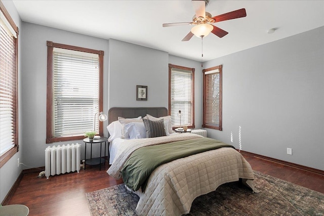 bedroom with radiator, a ceiling fan, baseboards, and wood finished floors