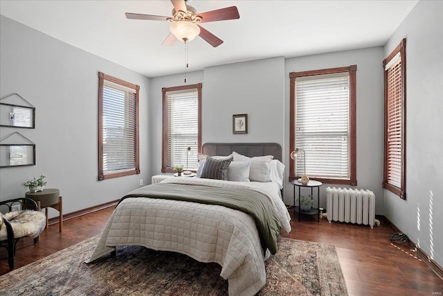 bedroom with multiple windows, radiator, wood finished floors, and baseboards