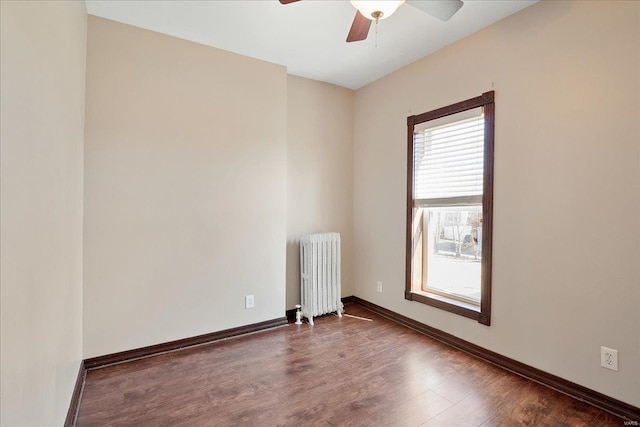 unfurnished room featuring radiator, a ceiling fan, baseboards, and wood finished floors