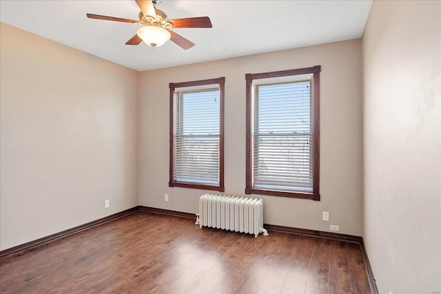 empty room with baseboards, radiator heating unit, ceiling fan, and wood finished floors