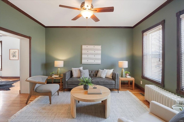 living room with radiator, crown molding, baseboards, and wood finished floors