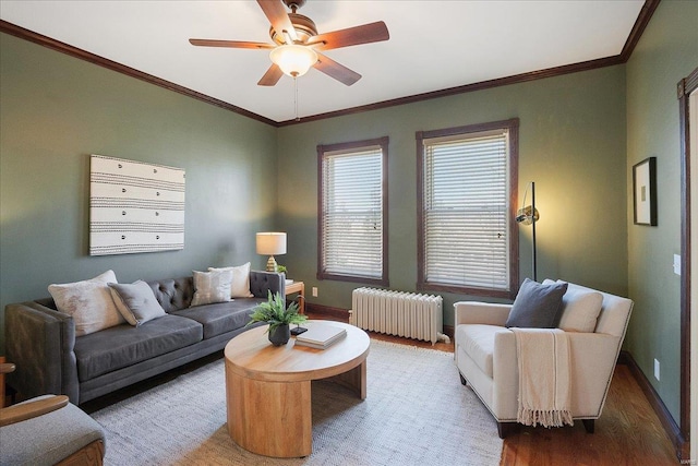 living area featuring radiator heating unit, wood finished floors, baseboards, and ornamental molding