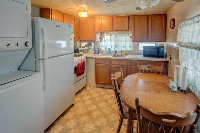 kitchen with stacked washer / dryer, sink, white appliances, and ceiling fan