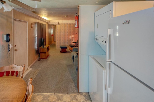 kitchen with stacked washer and dryer, white fridge, and wooden walls