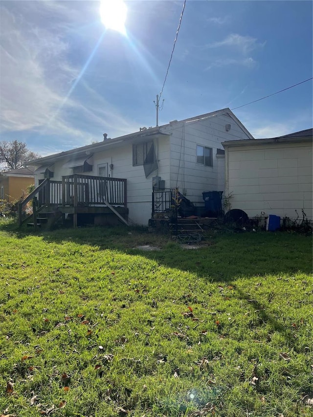 rear view of house featuring a wooden deck and a yard