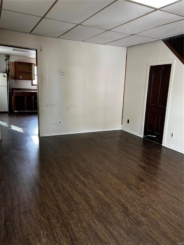 unfurnished room featuring dark wood-type flooring and a drop ceiling