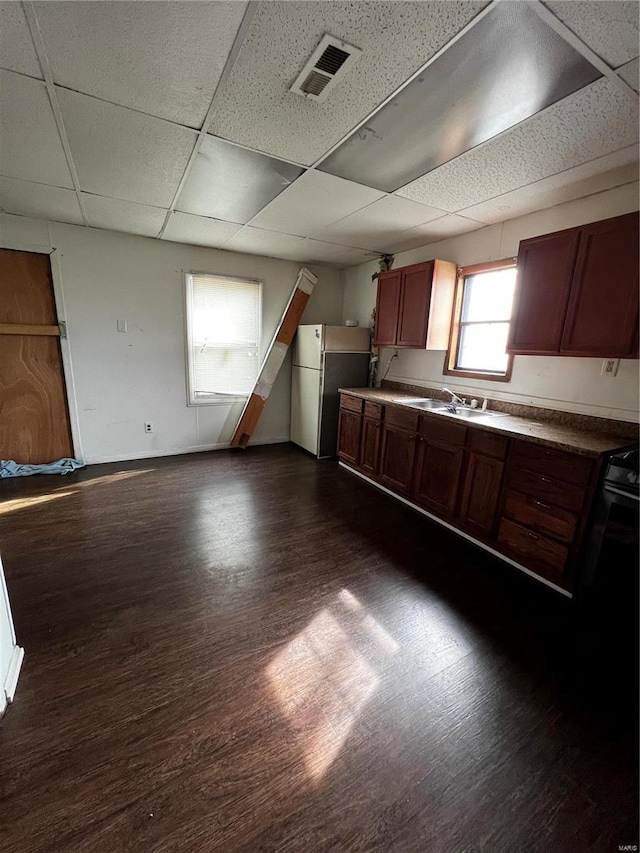 kitchen featuring sink, stainless steel fridge, a paneled ceiling, range, and dark hardwood / wood-style flooring