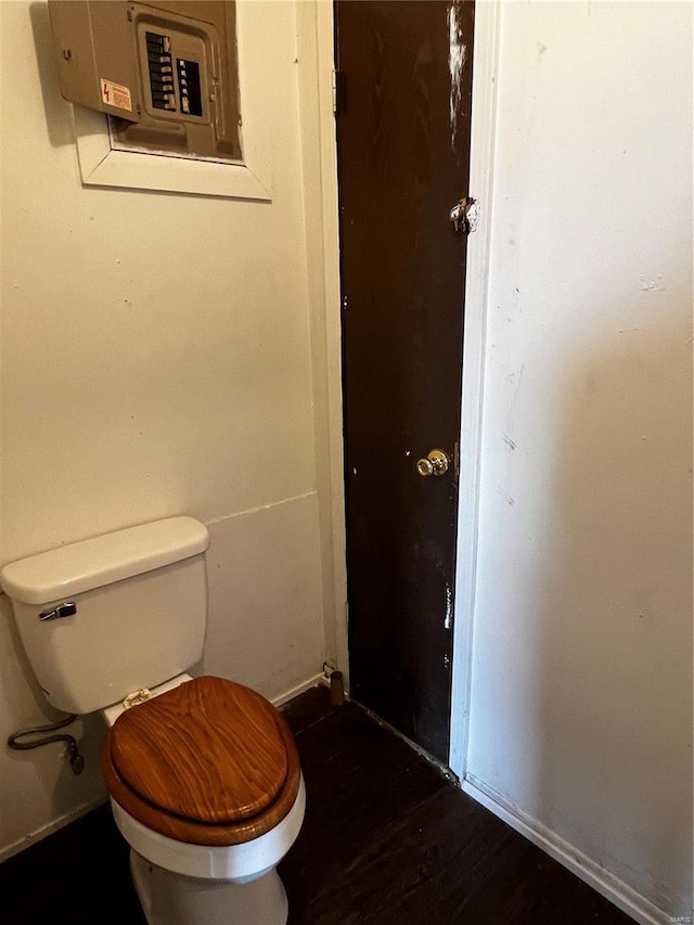 bathroom featuring wood-type flooring, toilet, and electric panel