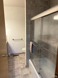 bathroom featuring enclosed tub / shower combo and toilet