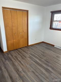 unfurnished bedroom with a closet and dark hardwood / wood-style flooring