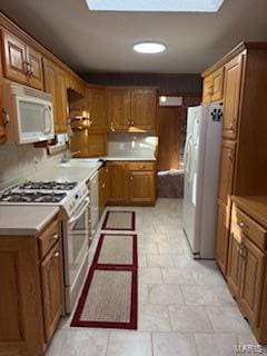 kitchen with sink, white appliances, and a skylight