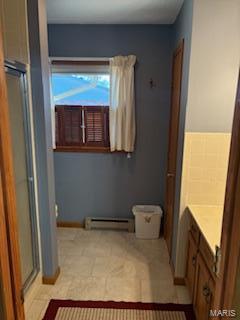 bathroom featuring a shower with door, a baseboard heating unit, and vanity