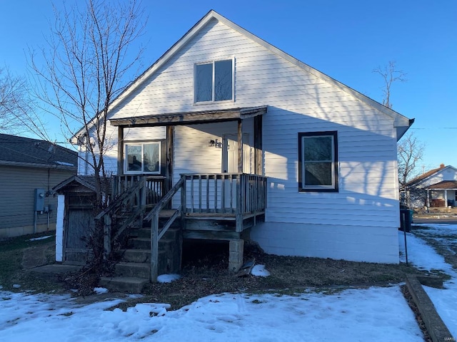 snow covered house featuring a porch