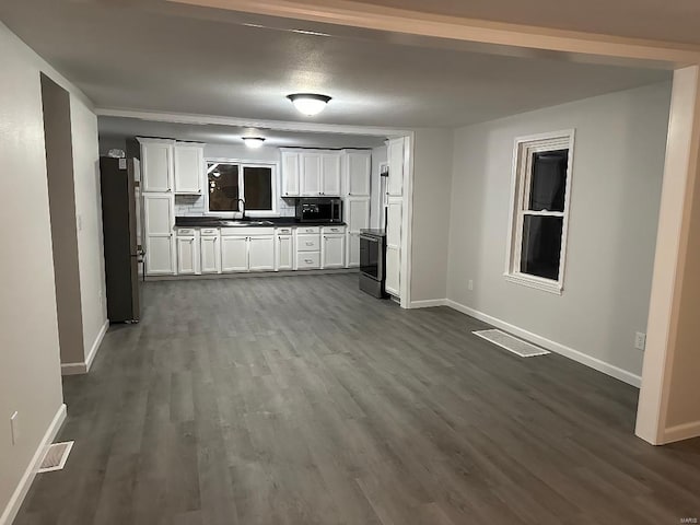 kitchen with dark wood finished floors, freestanding refrigerator, a sink, black microwave, and baseboards