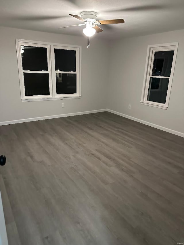 unfurnished room with baseboards, dark wood finished floors, and a ceiling fan